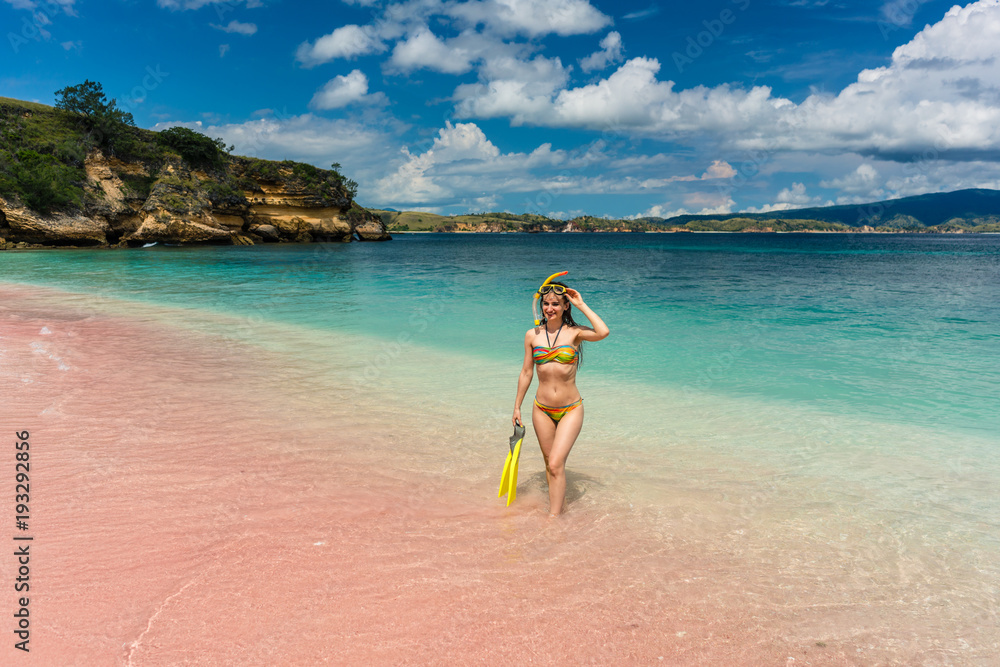 Beautiful young woman holding snorkeling equipment at Pink Beach Beautiful young woman holding snorkeling equipment at Pink Beach