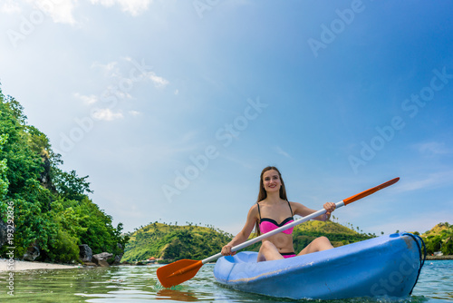 Young woman paddling during vacation in an idyllic travel destin