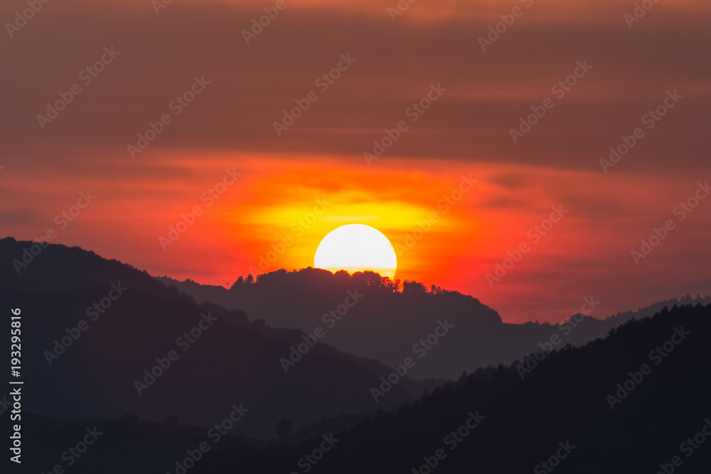 Beautiful landscape of a big setting sun over the silhouette of the mountains, Salciua, Romania Beautiful landscape of a big setting sun over the silhouette of the mountains, Salciua, Romania