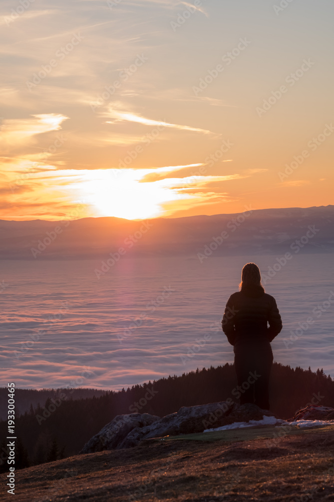 Woman on mountain Schoeckl looking over low stratus to sunset