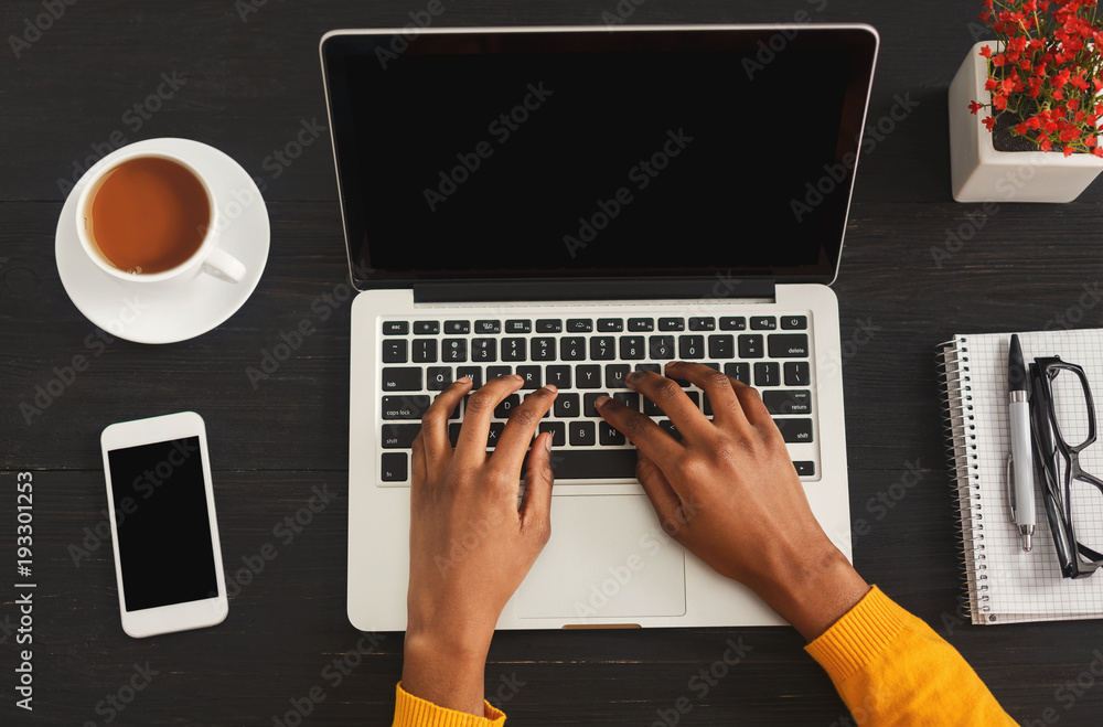 Fototapeta premium Black female hands typing on laptop keyboard, top view