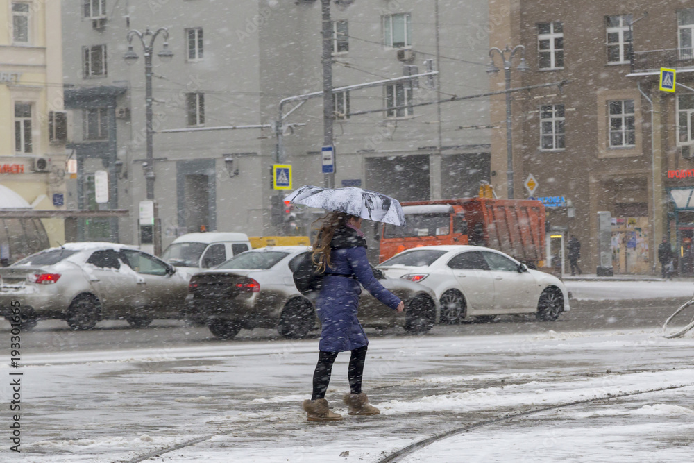Moscow, Russia. A young woman with an umbrella is walking along the Tverskaya Zastava square