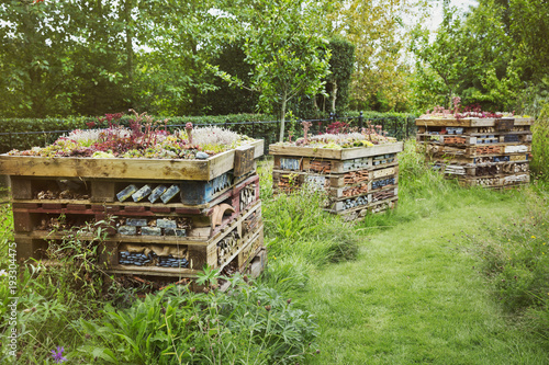 Three large bug houses with several layers of different materials in a garden.