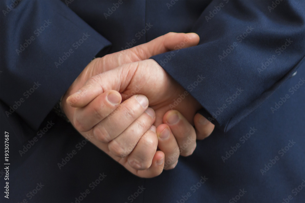 Closeup of a business man with his hands behind his back.