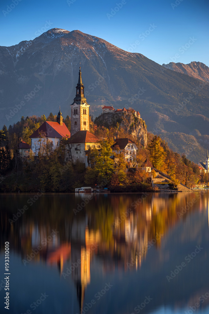 Bled, Slovenia - Lake Bled on a beautiful autumn morning with the famous Pilgrimage Church of the Assumption of Maria and Bled Castle and Julian Alps at background. Clear blue sky