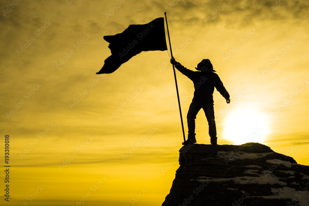 silhouette of man on top of mountain with victory flag, background sky