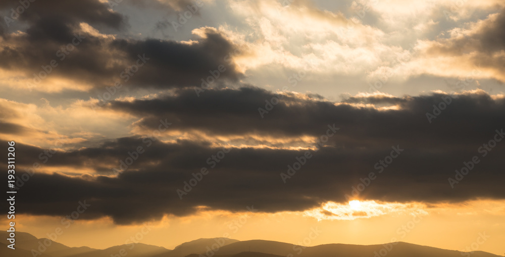 Sunrise or sunset over mountains silhouette. Sunbeams come through the colorful clouds. Space, banner. Sunrise or sunset over mountains silhouette. Sunbeams come through the colorful clouds. Space, banner.