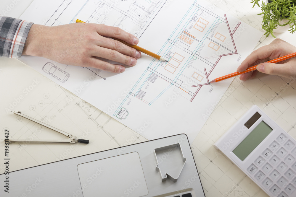 Architects working on blueprint, real estate project. Architect workplace - architectural project, blueprints, ruler, calculator, laptop and divider compass. Construction concept. Engineering tools. Architects working on blueprint, real estate project. Architect workplace - architectural project, blueprints, ruler, calculator, laptop and divider compass. Construction concept. Engineering tools.