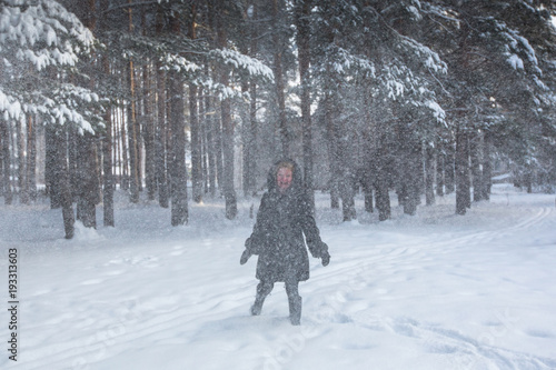 Young woman in the forest in a strong snowstorm.