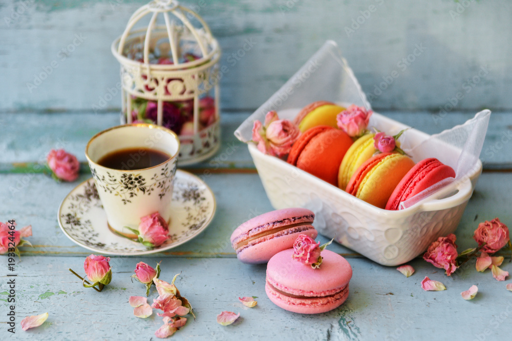 Dessert With Coffee: A Delicate Fresh French Macaroons In Pastel Colors Gift Box Flowers Roses On Light Blue Wooden Background Dessert With Coffee: A Delicate Fresh French Macaroons In Pastel Colors Gift Box Flowers Roses On Light Blue Wooden Background