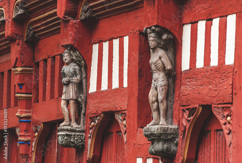 Historic red half-timbered house with wooden statues on facade in old town in Rennes, Brittany, France