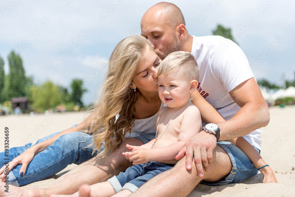 Young family with a toddler resting on the beach.