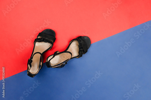 Black wedge-heeled sandals on red and blue background. Fashion concept