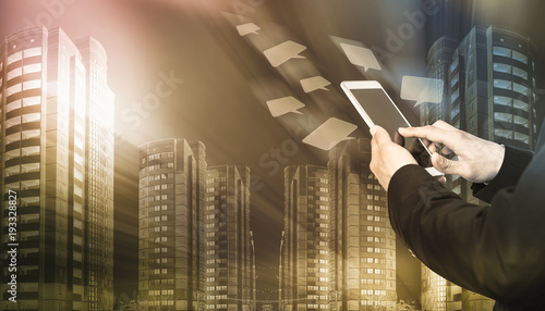 Male hands with smartphone on icons flying and skyscrapers background photo