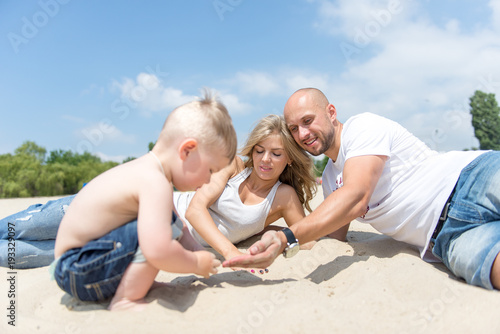 Young family with a toddler resting on the beach.