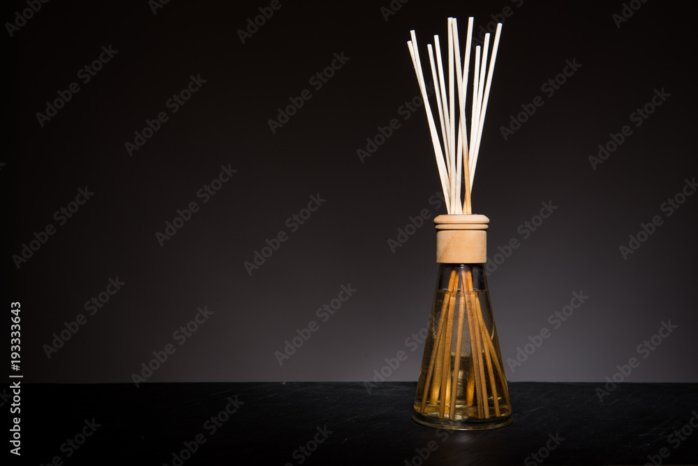 aroma liquid in a glass bottle with reed sticks isolated on black background. aroma liquid in a glass bottle with reed sticks isolated on black background.