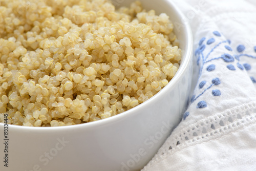 Cooked quinoa in a white bowl on a blue and white napkin