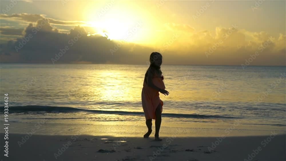 Adorable happy little girl have a lot of fun on white beach at sunset. SLOW MOTION Adorable happy little girl have a lot of fun on white beach at sunset. SLOW MOTION