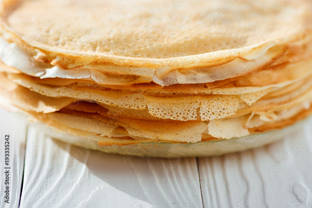 A stack of pancakes - Russian traditional dish. Thin delicious pancakes in a plate on a white background A stack of pancakes - Russian traditional dish. Thin delicious pancakes in a plate on a white background