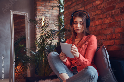 A charming brunette in casual clothes with a tablet and headphon photo