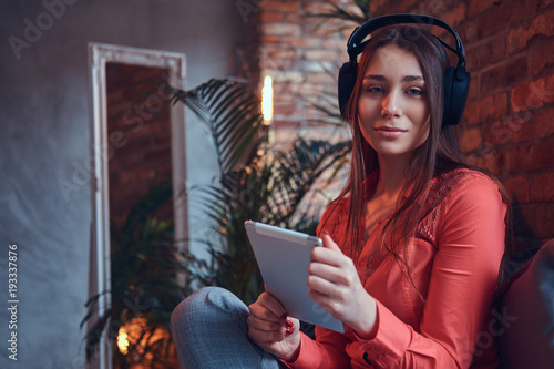 A charming brunette in casual clothes with a tablet and headphon photo