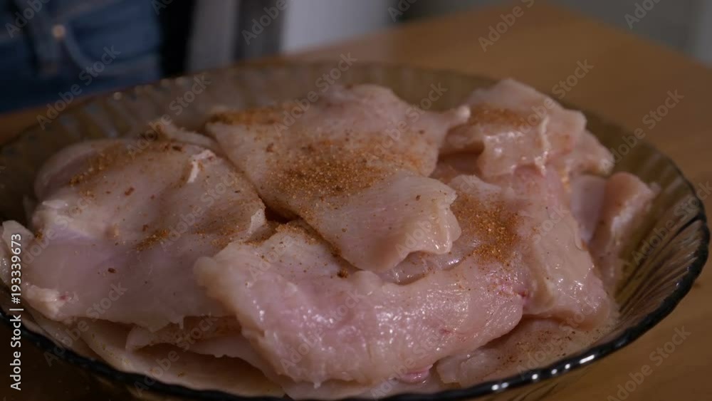 Closeup of young cook woman seasoning sliced chicken meat with spices and oil Closeup of young cook woman seasoning sliced chicken meat with spices and oil