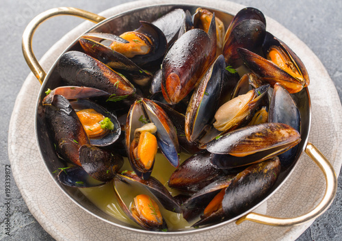 Mussels cooked in wine sauce with herbs in a frying pan