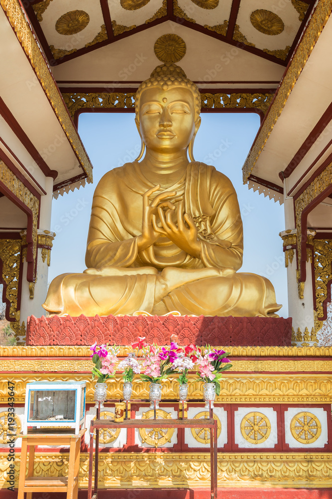 Front view of a golden statue of Buddha in lotus position on the Sagaing Hill in Mandalay, Myanmar (Burma) on a sunny day. Front view of a golden statue of Buddha in lotus position on the Sagaing Hill in Mandalay, Myanmar (Burma) on a sunny day.