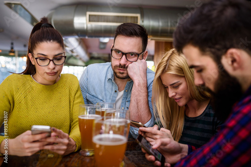 Man is getting bored in the bar while others using their smartphones photo
