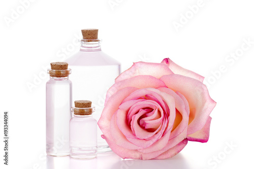 Pink rose and three glass bottles with transparent liquid