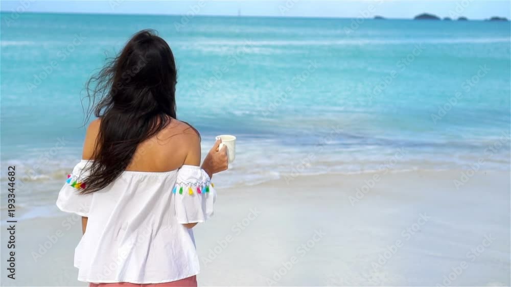 Young woman with hot coffee on white tropical beach. SLOW MOTION Young woman with hot coffee on white tropical beach. SLOW MOTION