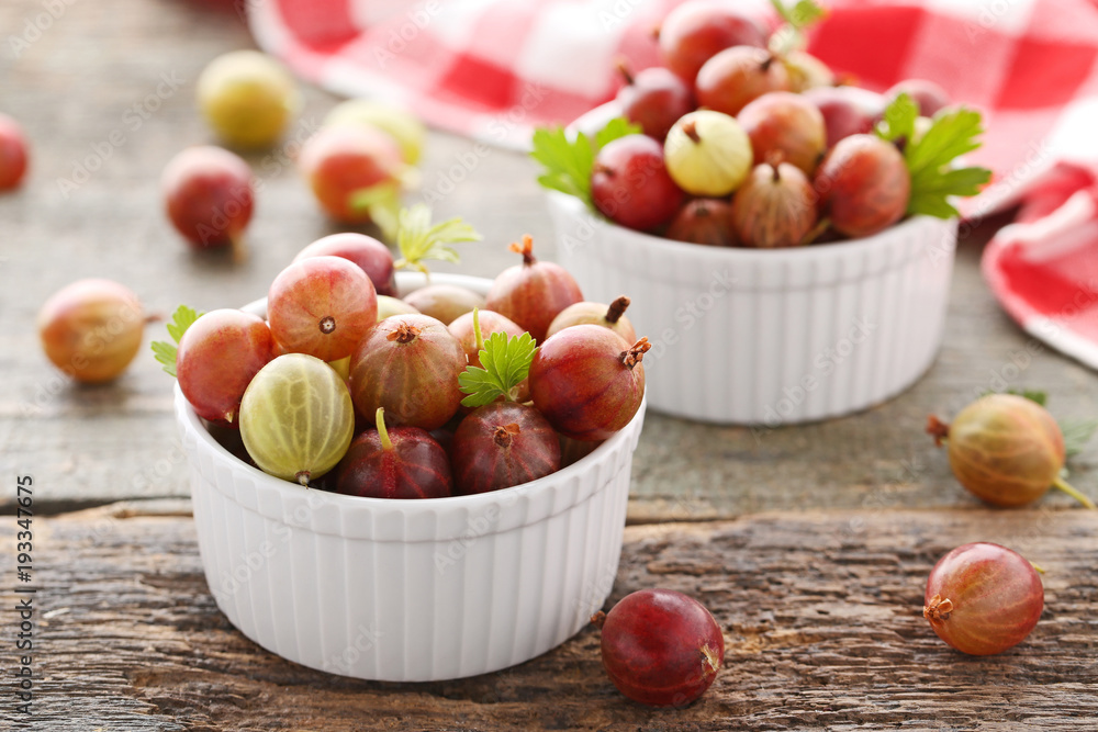 Ripe gooseberries fruit in bowl on wooden table Ripe gooseberries fruit in bowl on wooden table