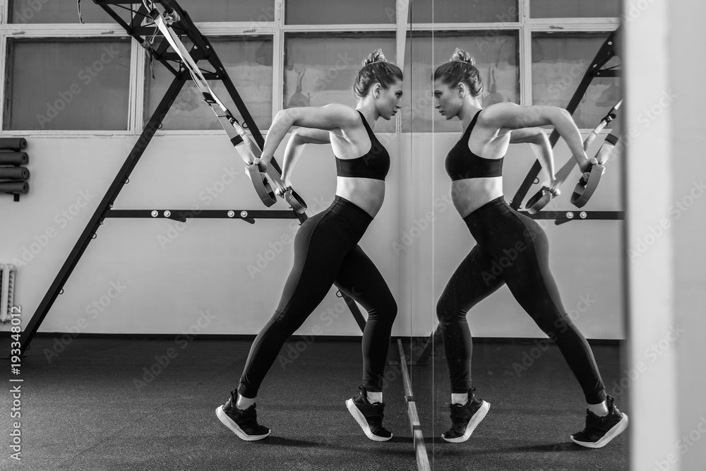 Sporty woman doing TRX exercises in the gym Sporty woman doing TRX exercises in the gym