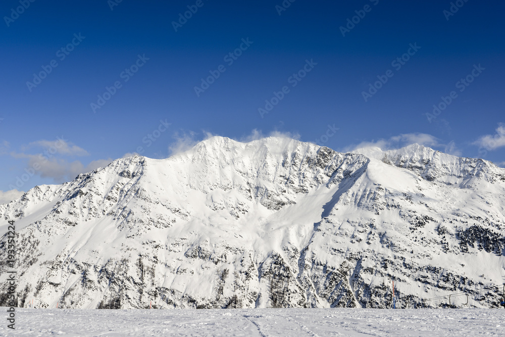 Stunning view of high mountain peaks in the italian alpine arc, in a bright sunny day and lot of candid snow