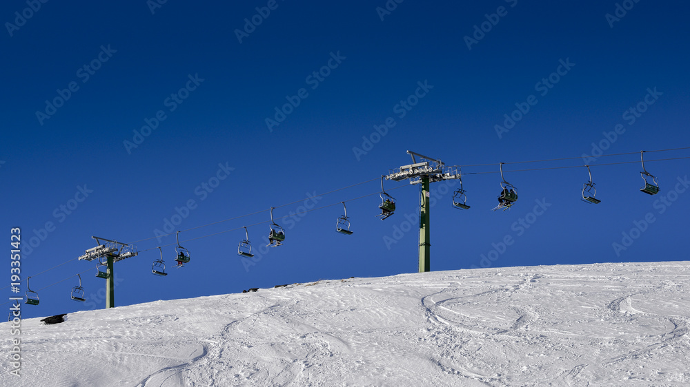 Winding snowboard trace and chairlift shadow on white snow Winding snowboard trace and chairlift shadow on white snow