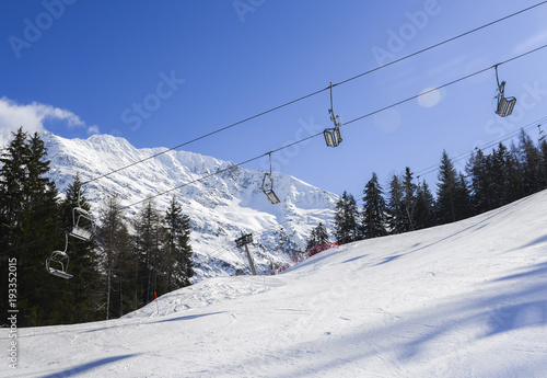 Chairlift at Italian ski area on snow covered Alps and pine trees © Alexandre Rotenberg