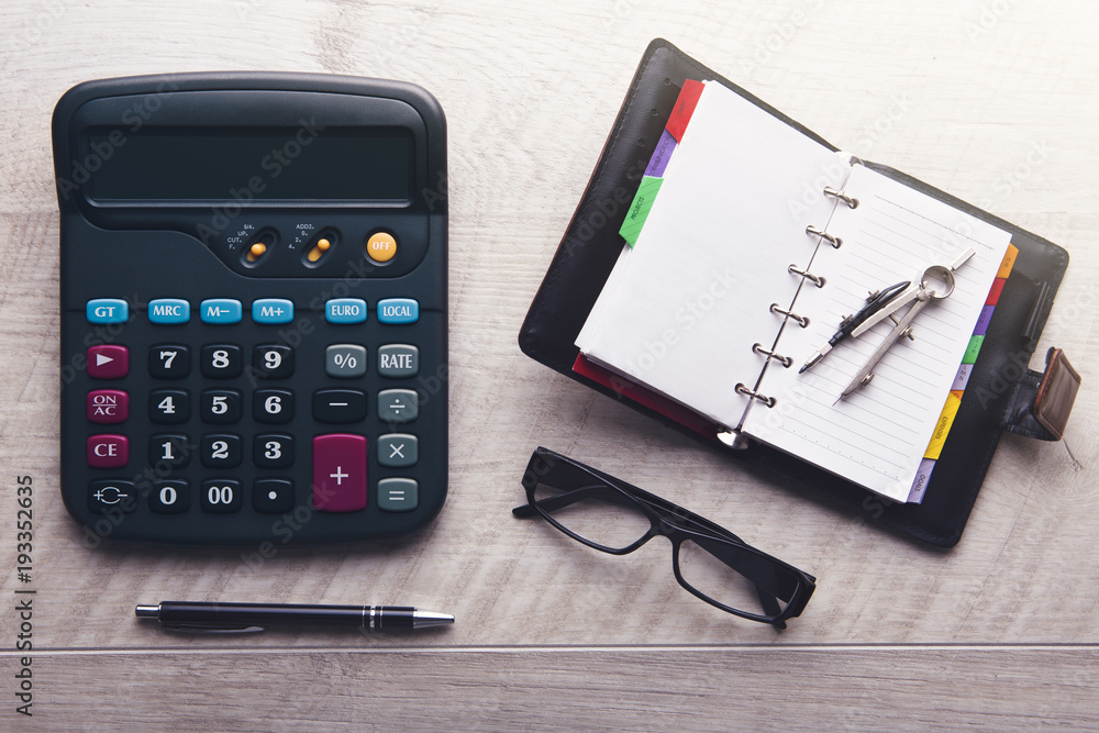 Top view of calculator, memo pad, glasses and pen in office Top view of calculator, memo pad, glasses and pen in office