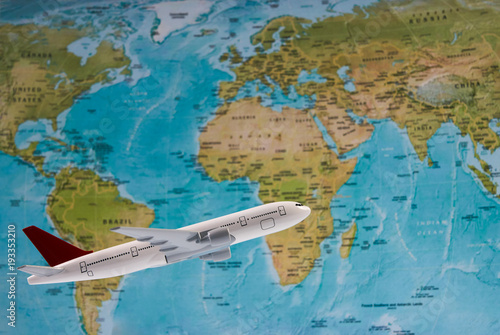 Traveling, tourism, international flights with flying airplane model and worldmap, close-up. White toy plane on the world map background. Travel concept