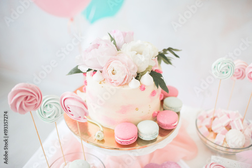 Pink cake with fresh flowers. White Wedding Cake. Colored cupcakes and macaroni.