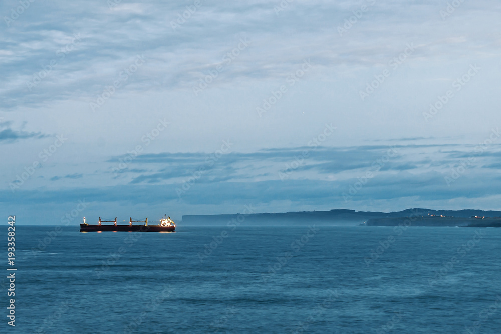 Beautiful coast landscape at dusk showing cliffs and freighter in the horizon Beautiful coast landscape at dusk showing cliffs and freighter in the horizon