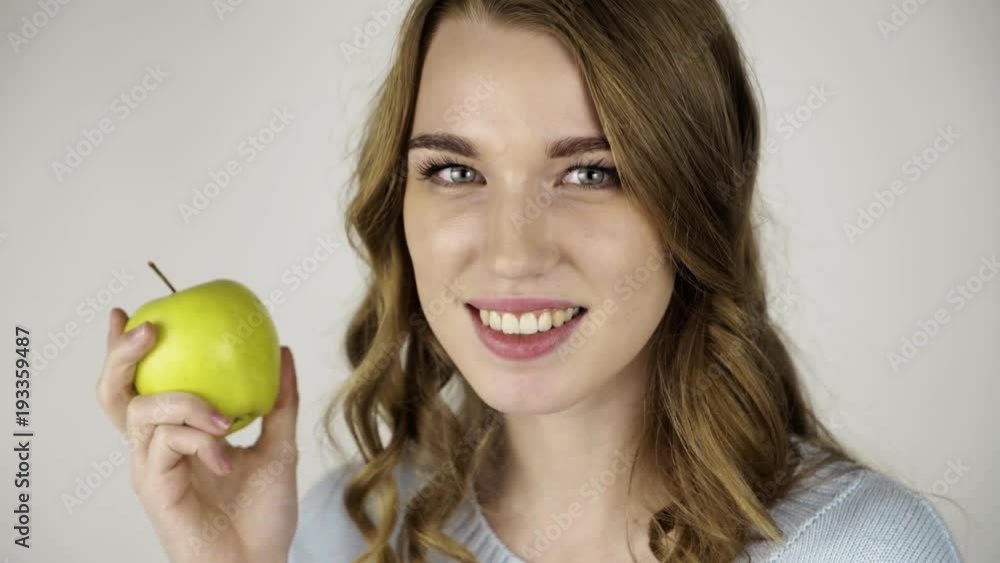 Seductive fair haired woman in gray holding a green juicy apple and flirting. Locked down real time close up shot Seductive fair haired woman in gray holding a green juicy apple and flirting. Locked down real time close up shot