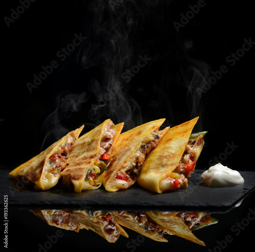 Mexican Quesadilla wrap with chicken   sweet pepper sour cream and salsa hot with steam smoke photo