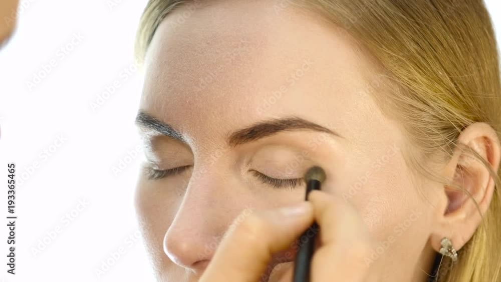 Close-up of professional make-up artist doing everyday makeup, puts powder on womans cheeks with brush Close-up of professional make-up artist doing everyday makeup, puts powder on womans cheeks with brush