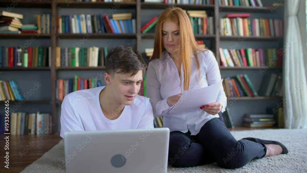 Male and female students learning and Using Laptop in the library. Two students brainstorming work by discuss with desktop in trendy loft close up with background books. High school friends meeting in Male and female students learning and Using Laptop in the library. Two students brainstorming work by discuss with desktop in trendy loft close up with background books. High school friends meeting in