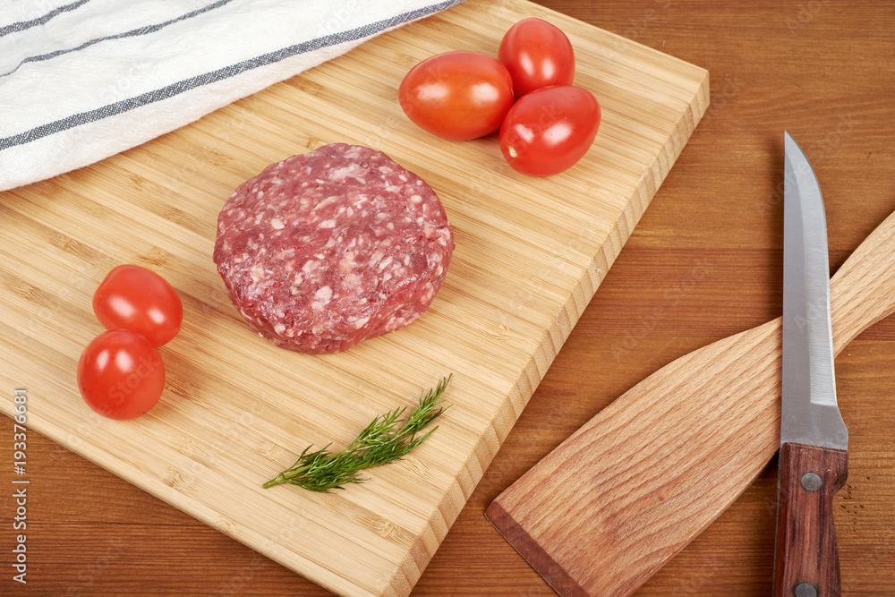 Raw cutlet of minced meat on a wooden cutting board. Raw cutlet of minced meat on a wooden cutting board.