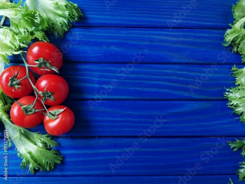 помидоры черри и зеленый салат на синем деревянном фоне