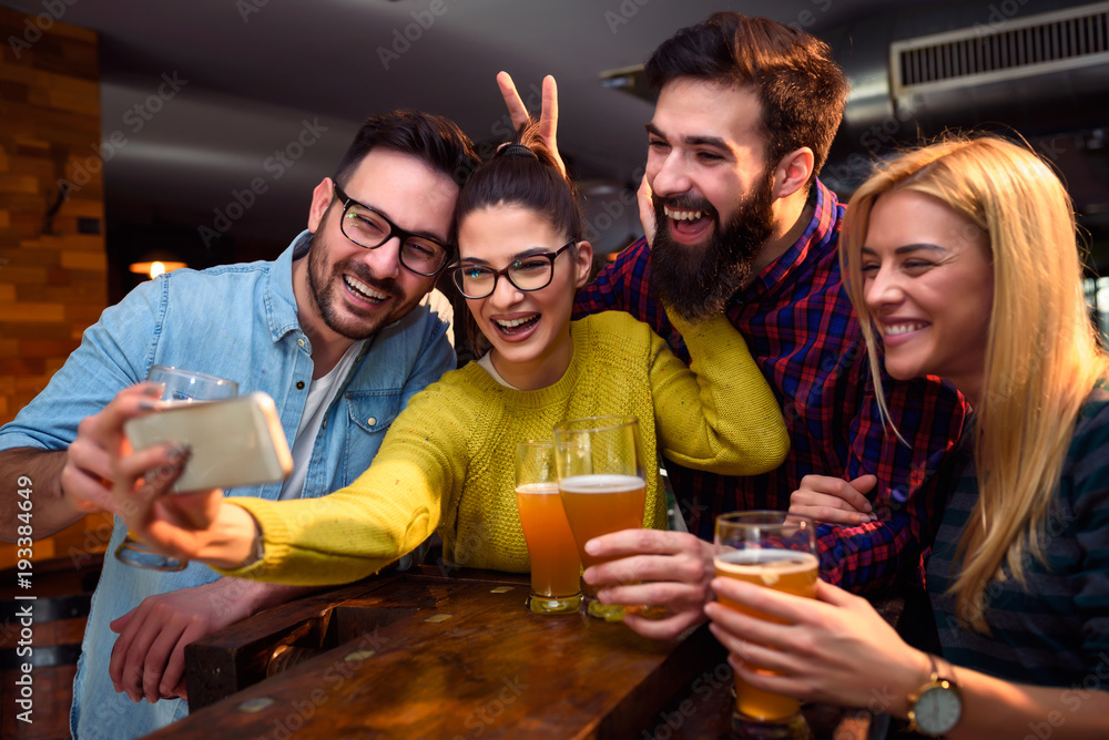 Group of young friends in bar drinking beer having fun