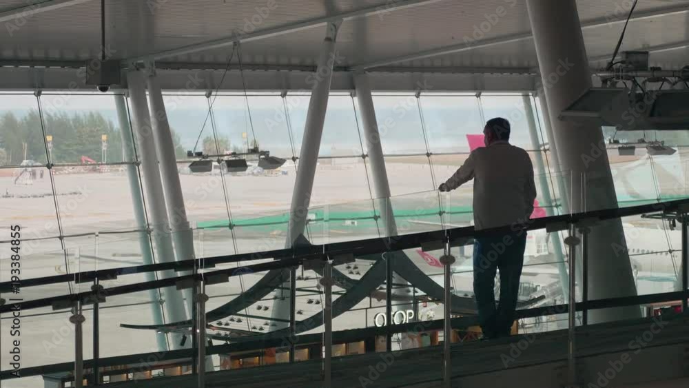 Unrecognizable male passenger walking along the airport to Gate 12 at the airport in Phuket International Airport on January 1, 2017. Unrecognizable male passenger walking along the airport to Gate 12 at the airport in Phuket International Airport on January 1, 2017.