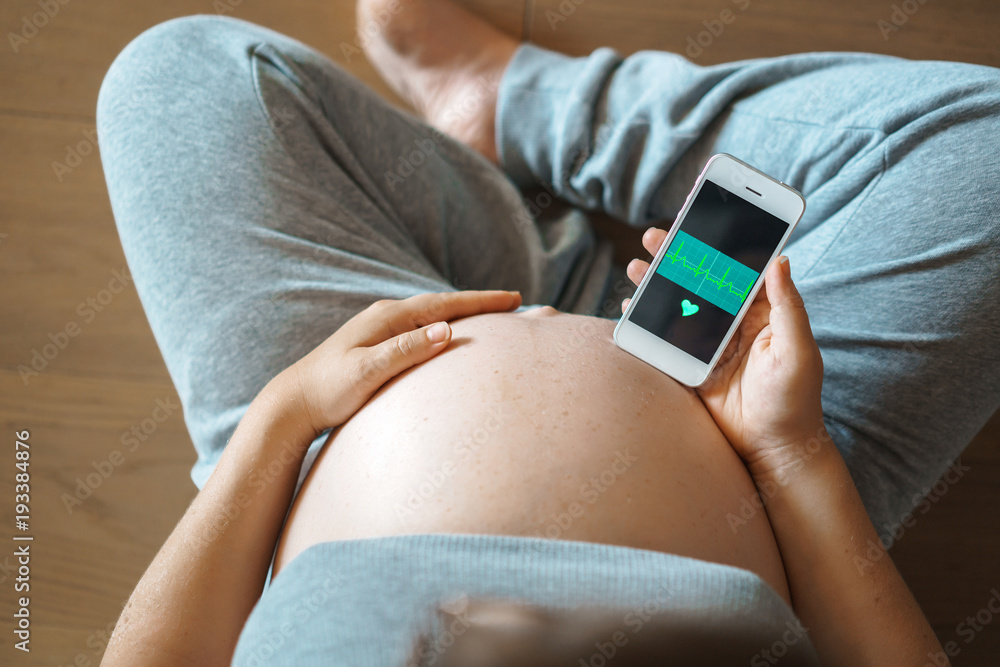 Check the heartbeat of the baby in the womb on your smartphone. The concept of pregnancy and technologies. Check the heartbeat of the baby in the womb on your smartphone. The concept of pregnancy and technologies.