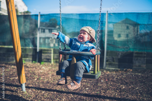 Happy little boy on swing in playground